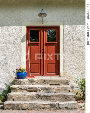 Old brown wooden entrance door with stone staris and flowers 86022044
