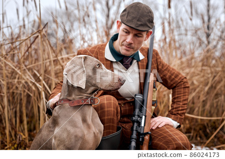 Hunting period, autumn season open. hunter with gun in suit in the autumn forest 86024173