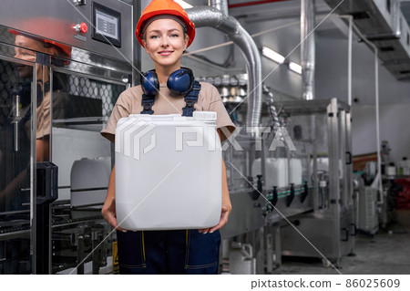 Nice engineer woman in hardhat holding pesticide canister bottle, posing. 86025609