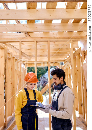 Two civil engineers dressed in uniform explore construction documentation Two civil engineers dressed in uniform explore construction documentation 86025782