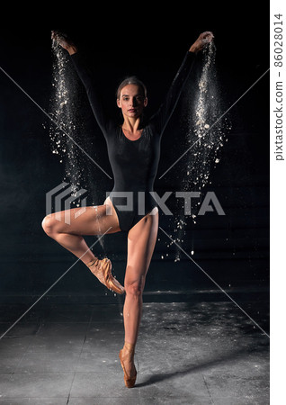 Ballet dancer dancing with flour on black studio background. Dancer in black bodysuit 86028014