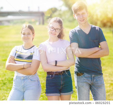 Teenagers with arms crossed are standing on the spring lawn 86028201