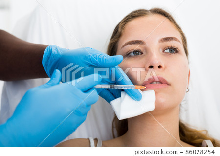 Young woman getting procedure of lip augmentation in cosmetology clinic 86028254