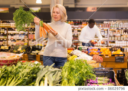 Pensive adult woman buying fresh vegetables Pensive adult woman buying fresh vegetables 86029796