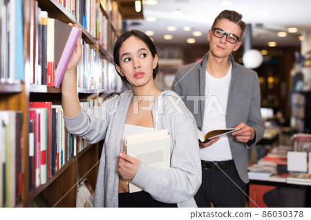 female choosing books attracted attention of guy female choosing books attracted attention of guy 86030378