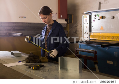 Woman working with metal sheet and using measuring tape Woman working with metal sheet and using measuring tape 86030461