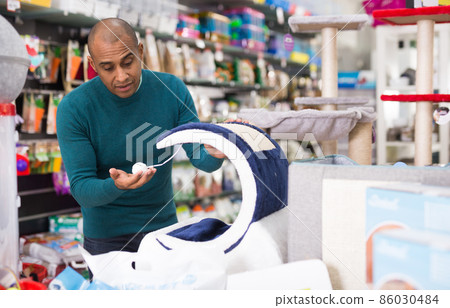 Man choosing cat furniture supplies in shop Man choosing cat furniture supplies in shop 86030484