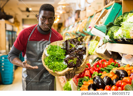 Greengrocery owner offering greens and leaf vegetables 86030572