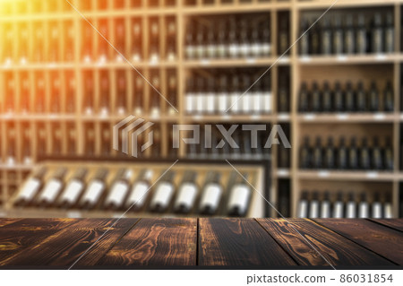 Wine wooden table background. Blurred wine shop with bottles on the counter. 86031854