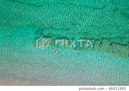 Top view. Young beautiful naked woman in a hat swimming in sea water on sand beach. Drone, copter photo. Summer vacation. View from above. Top view. Young beautiful naked woman in a hat swimming in sea water on sand beach. Drone, copter photo. Summer vacation. View from above. 86031893