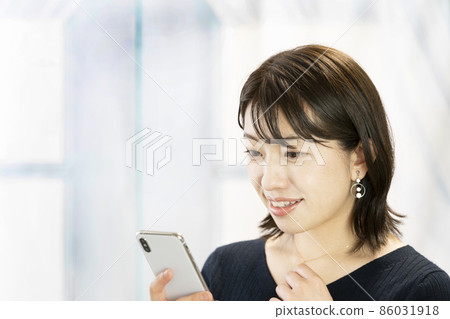 A woman who smiles at the screen of her smartphone 86031918