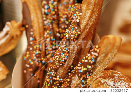 Churros waffles in a hand on the winter snow market. Churros Mexican street food dessert. Fast food sweets, Christmas fair cookies 86032457