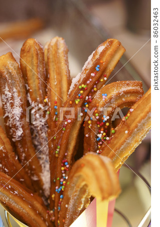 Churros waffles in a hand on the winter snow market. Churros Mexican street food dessert. Fast food sweets, Christmas fair cookies 86032463
