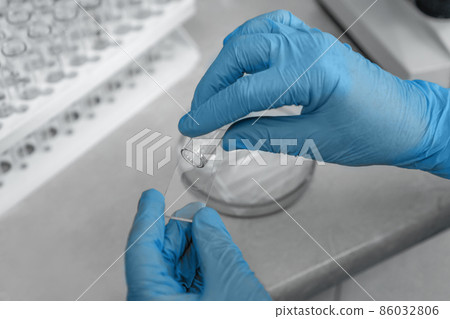 Medical equipment. Hand in protective gloves holding medicine glass and test tube. Vaccine creation concept. The doctor, scientist is making a coronavirus test. Protection of omicron, delta, Covid-19  86032806