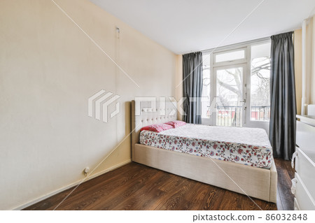 Charming bedroom area with a cute bed covered with a floral bedspread 86032848