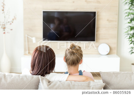 Mother and daughter sitting on sofa and watching tv, single mother concept, back view 86035926