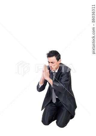 Well dressed man praying on knees in studio 86036311