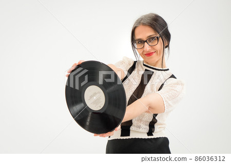 Studio photo of middle aged woman starting getting grey-haired wearing black and white clothes with vinyl record in hands on white background, middle age sexy lady, happy life concept 86036312
