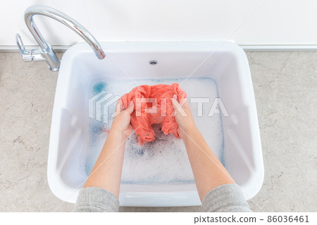 Female hands washing color clothes in sink Female hands washing color clothes in sink 86036461