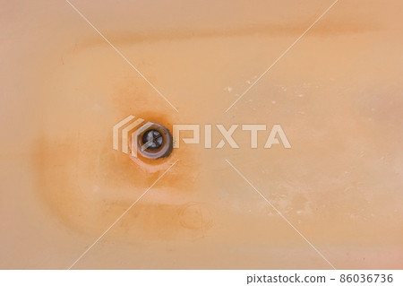 Old dirty bath with rust and a hole for drain fluzing impure water into sewer Old dirty bath with rust and a hole for drain fluzing impure water into sewer 86036736
