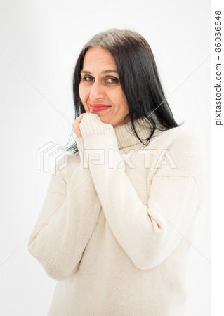 Middle aged woman starting getting grey-haired is posing in studio in sweater on white background, face skin care beauty, middle age skincare cosmetics, cosmetology concept Middle aged woman starting getting grey-haired is posing in studio in sweater on white background, face skin care beauty, middle age skincare cosmetics, cosmetology concept 86036848