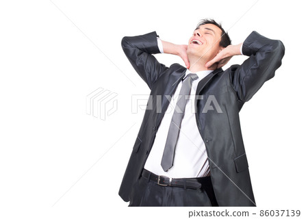 Happy man in suit touching neck against white wall Happy man in suit touching neck against white wall 86037139