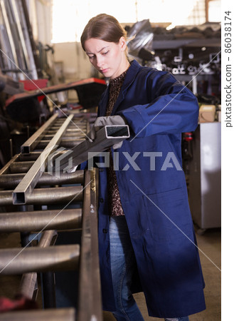 Woman worker with metal beams during work in workshop Woman worker with metal beams during work in workshop 86038174