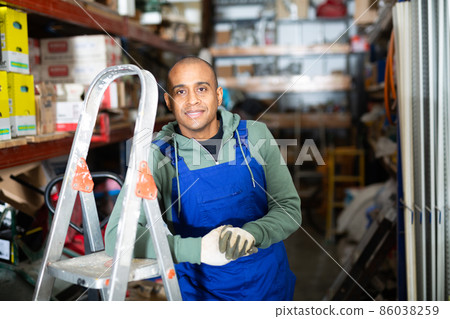 Hispanic worker of building materials warehouse near racks with goods Hispanic worker of building materials warehouse near racks with goods 86038259