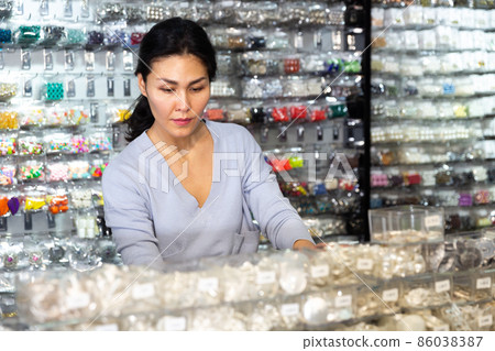 Asian female shopper looking for costume jewelry in showroom Asian female shopper looking for costume jewelry in showroom 86038387