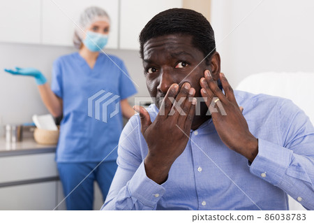 Portrait of unhappy worried afro american man after cosmetic procedure Portrait of unhappy worried afro american man after cosmetic procedure 86038783