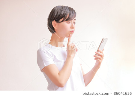 A woman with a puffy expression looking at her smartphone 1 A woman with a puffy expression looking at her smartphone 1 86041636