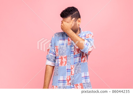 Don't want to look at this. Portrait of dark haired man in casual blue shirt covering eyes and turning with disgust from something shameful. Indoor studio shot isolated on pink background. Don't want to look at this. Portrait of dark haired man in casual blue shirt covering eyes and turning with disgust from something shameful. Indoor studio shot isolated on pink background. 86044235