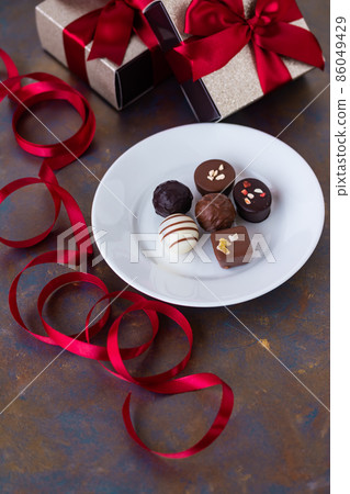Red ribbon present box and chocolate Red ribbon present box and chocolate 86049429