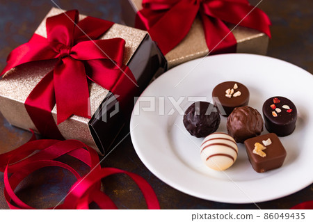 Red ribbon present box and chocolate Red ribbon present box and chocolate 86049435