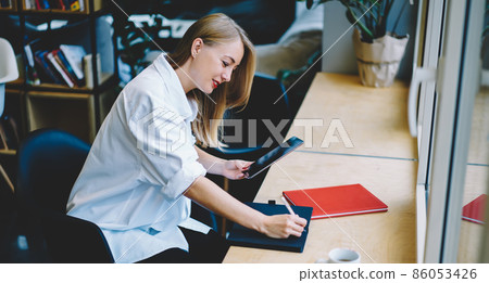 Young woman taking notes from tablet Young woman taking notes from tablet 86053426