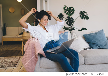 Excited woman watching funny video on laptop at home 86053509