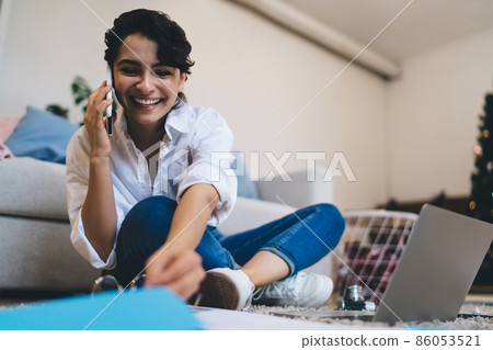Positive young woman talking on smartphone during work online 86053521