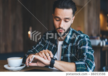 impressed hipster guy looking at touchscreen of smartwatch impressed hipster guy looking at touchscreen of smartwatch 86053598