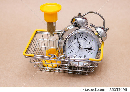 An hourglass and a metal alarm clock in the shopping basket. concept of time. 86055496