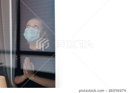 Quarantine woman in medical mask on face looking through the window. Copy space Quarantine woman in medical mask on face looking through the window. Copy space 86056974