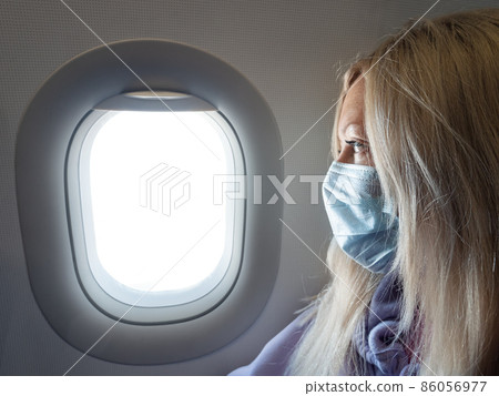 Woman wearing medical protective mask in airplane while flight. New normal travel during covid-19 pandemic situation Woman wearing medical protective mask in airplane while flight. New normal travel during covid-19 pandemic situation 86056977