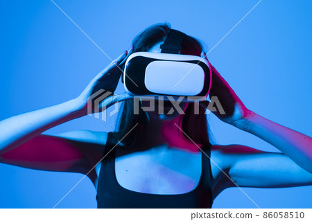 Brunette woman in vr glasses, watching 360 degree video with virtual reality headset illuminated by neon lights. Brunette woman in vr glasses, watching 360 degree video with virtual reality headset illuminated by neon lights. 86058510