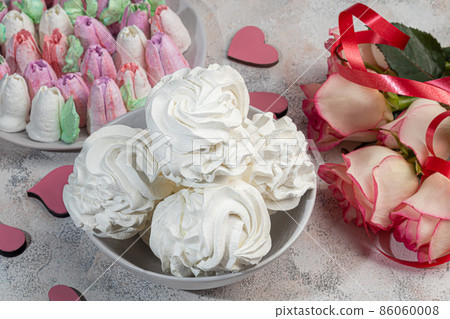 Handmade marshmallows on a light background in the form of roses, hydrangeas and tulips. There are flowers nearby. Women's day, Valentine's day. 86060008