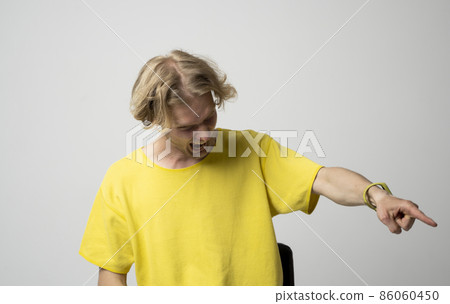 Young brutal angry man in yellow t-shirt screams on somebody over white background. Face expression. Crazy man. Negative emotions, problems. Stressed guy shouting. Young brutal angry man in yellow t-shirt screams on somebody over white background. Face expression. Crazy man. Negative emotions, problems. Stressed guy shouting. 86060450