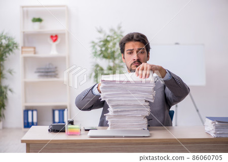 Young male employee and too much work in the office Young male employee and too much work in the office 86060705