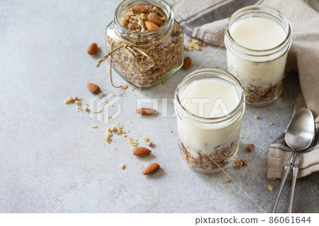 Healthy breakfast, yogurt parfait. Yogurt with homemade almond granola on a gray concrete background. Copy space. 86061644