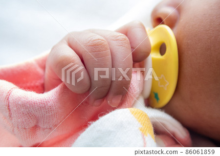 Baby's little hand holding a pacifier 86061859