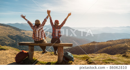 Couple of Hikers With Raised Hands in Front of Landscape Valley View on Top of a Mountain 86062810