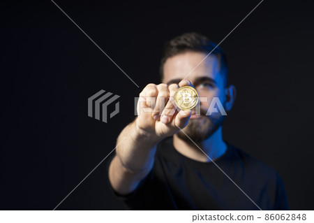 Golden Bitcoin in a young businessman hand. Digitall symbol of a new virtual currency. Cryptocurency. Golden Bitcoin in a young businessman hand. Digitall symbol of a new virtual currency. Cryptocurency. 86062848