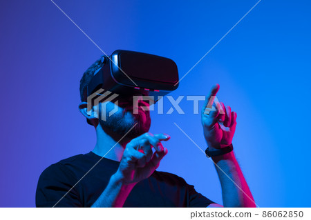 Happy and excited man playing racing video game with virtual reality headset in a metaverse world with a friends. Future technology concept. Happy and excited man playing racing video game with virtual reality headset in a metaverse world with a friends. Future technology concept. 86062850